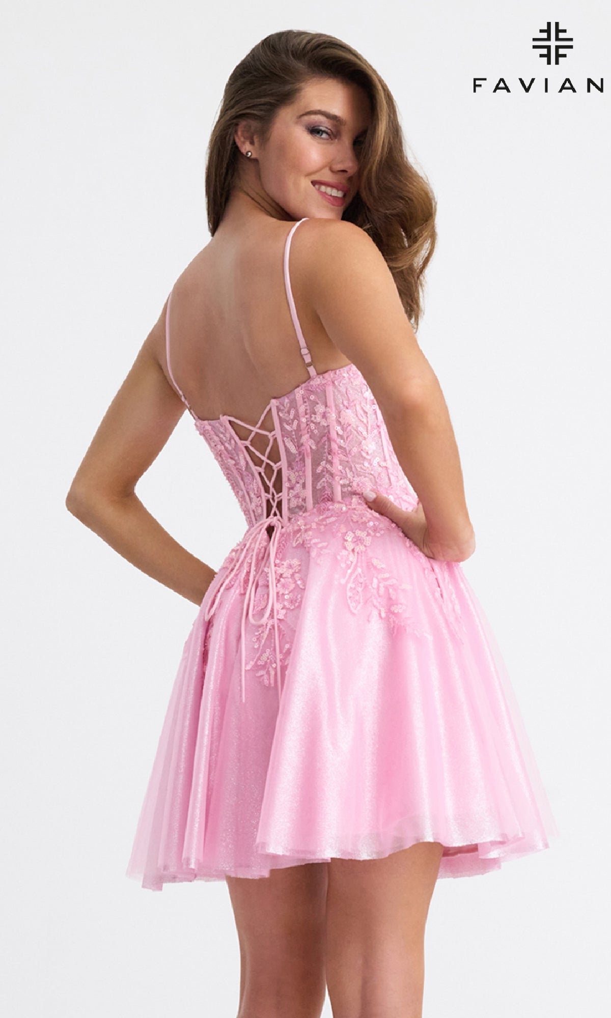 A woman smiles in the Faviana 11305 Short Fit-and-Flare Hoco Dress, featuring beaded floral appliqué, a light pink lace-up back, fitted bodice, and flared skirt.